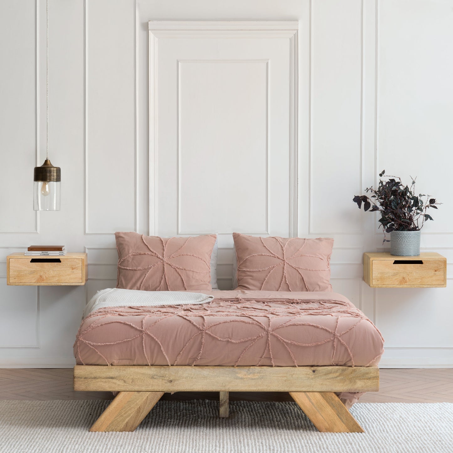 Bedroom with a wooden bed frame, pink bedding, and wall-mounted nightstands.